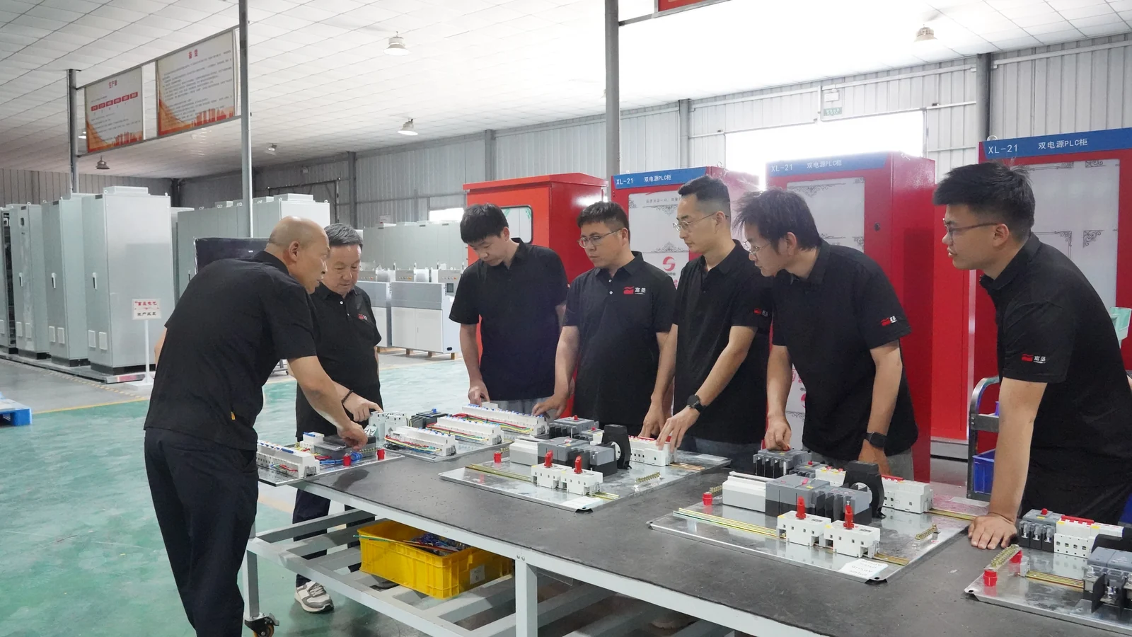 Team members gathered around electrical components at a workshop bench